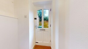 A white door with a glass panel and a small window, leading to a room with a visible door handle and a light switch on the wall. - Newly Refurbished 2-Bed Retreat in Aylsham – Perfect for Exploring North Norfolk (Aylsham)