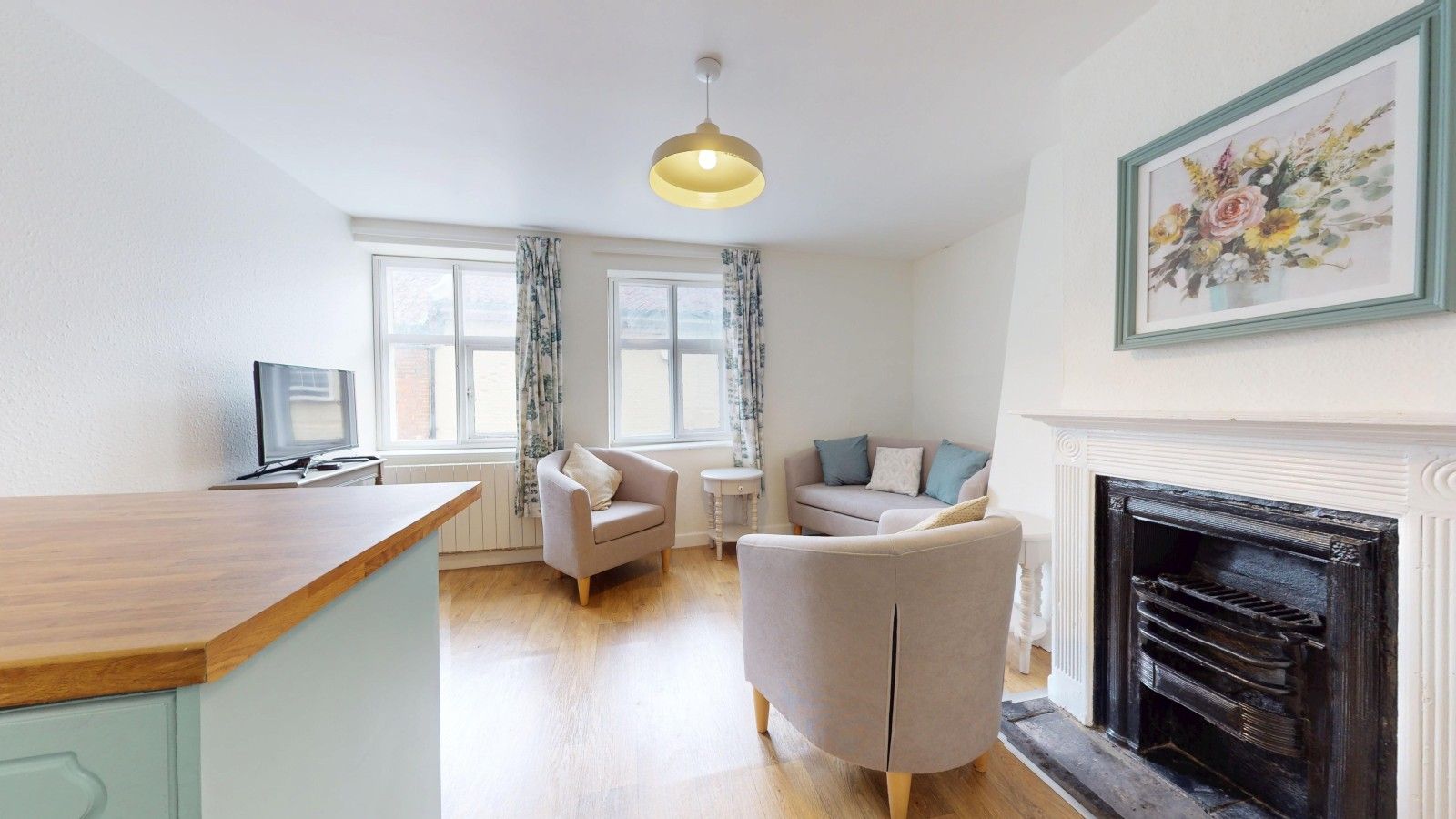 A modern living room with a fireplace, a dining area, and a kitchen with a wooden counter.
