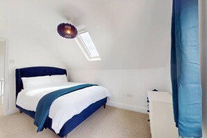 A bedroom with a bed, a bedside table, a hanging light fixture, and a window. - Sheringham Luxury, Cinema, Hot Tub & Beach (Norfolk)