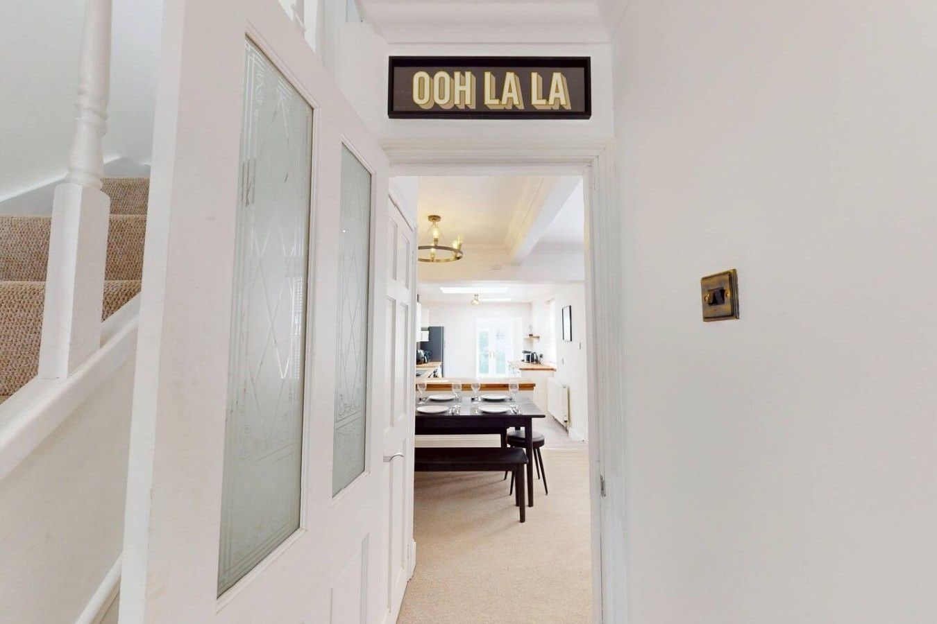 A hallway leading to a dining area with a sign reading 'OOH LA LA'.