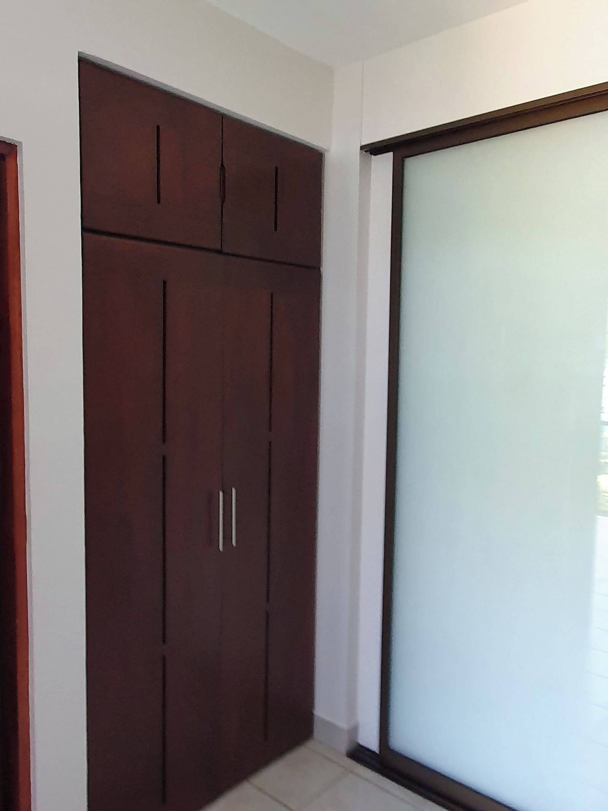 Una habitación con un armario grande, un ventanal corredero y suelo de baldosas.