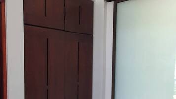 Una habitación con un armario grande, un ventanal corredero y suelo de baldosas.