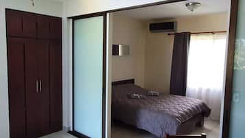 Un dormitorio con cama, armario, televisor y ventilador de techo.