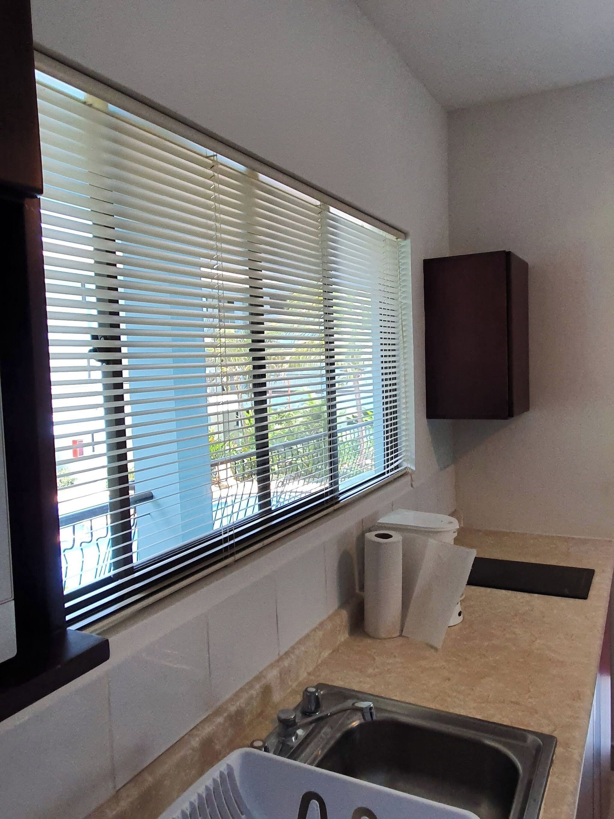 Una cocina con ventana, un lavamanos y un armario.