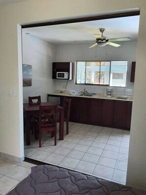 Una cocina con comedor, ventilador de techo, microondas y ventana con persianas.