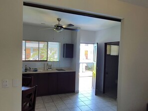 Una cocina con ventilador de techo, una ventana con persianas, un fregadero y una encimera.