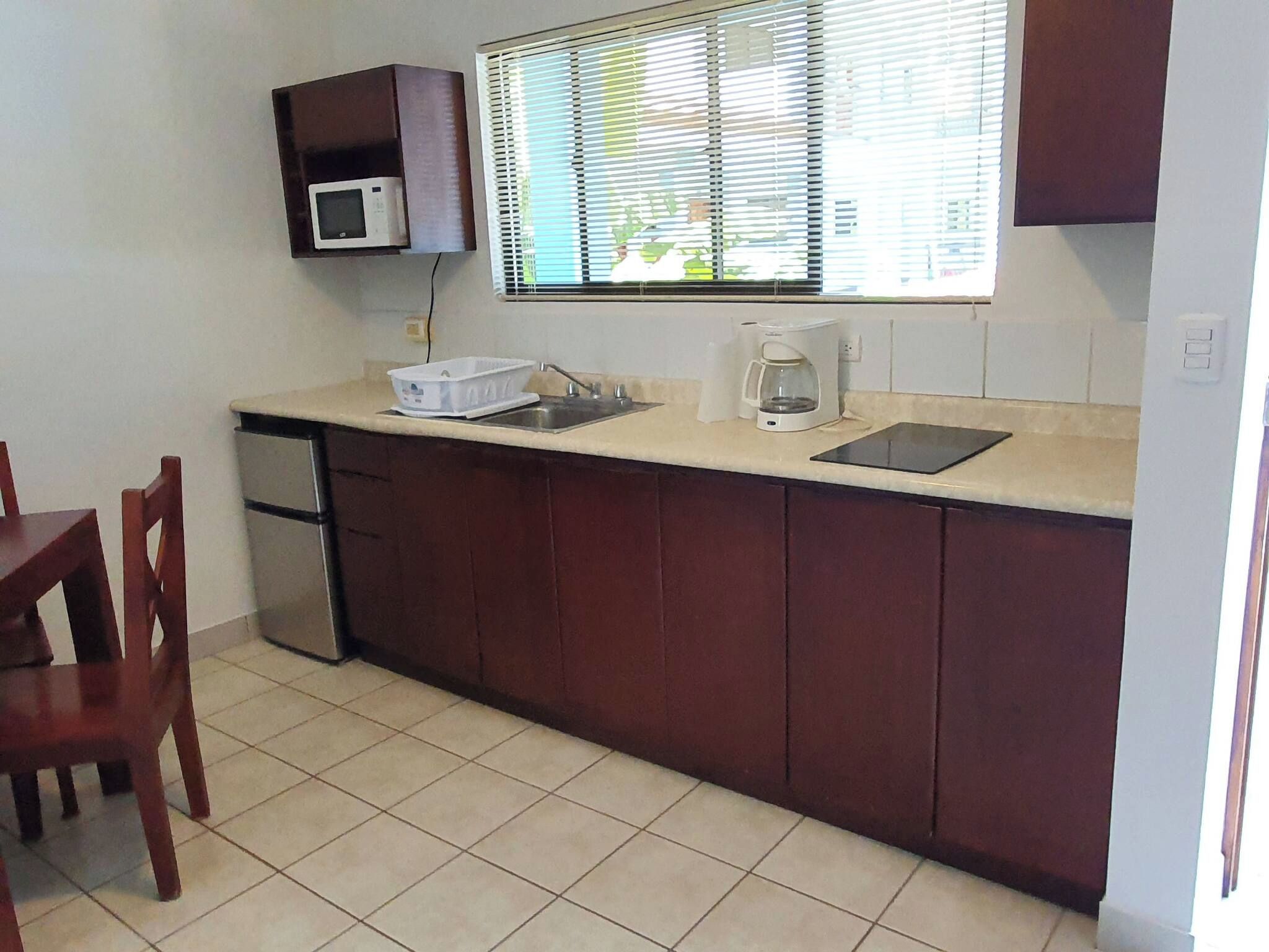 A compact kitchen with a microwave, coffee maker, and a sink.