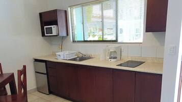 A compact kitchen with a microwave, coffee maker, and a sink.