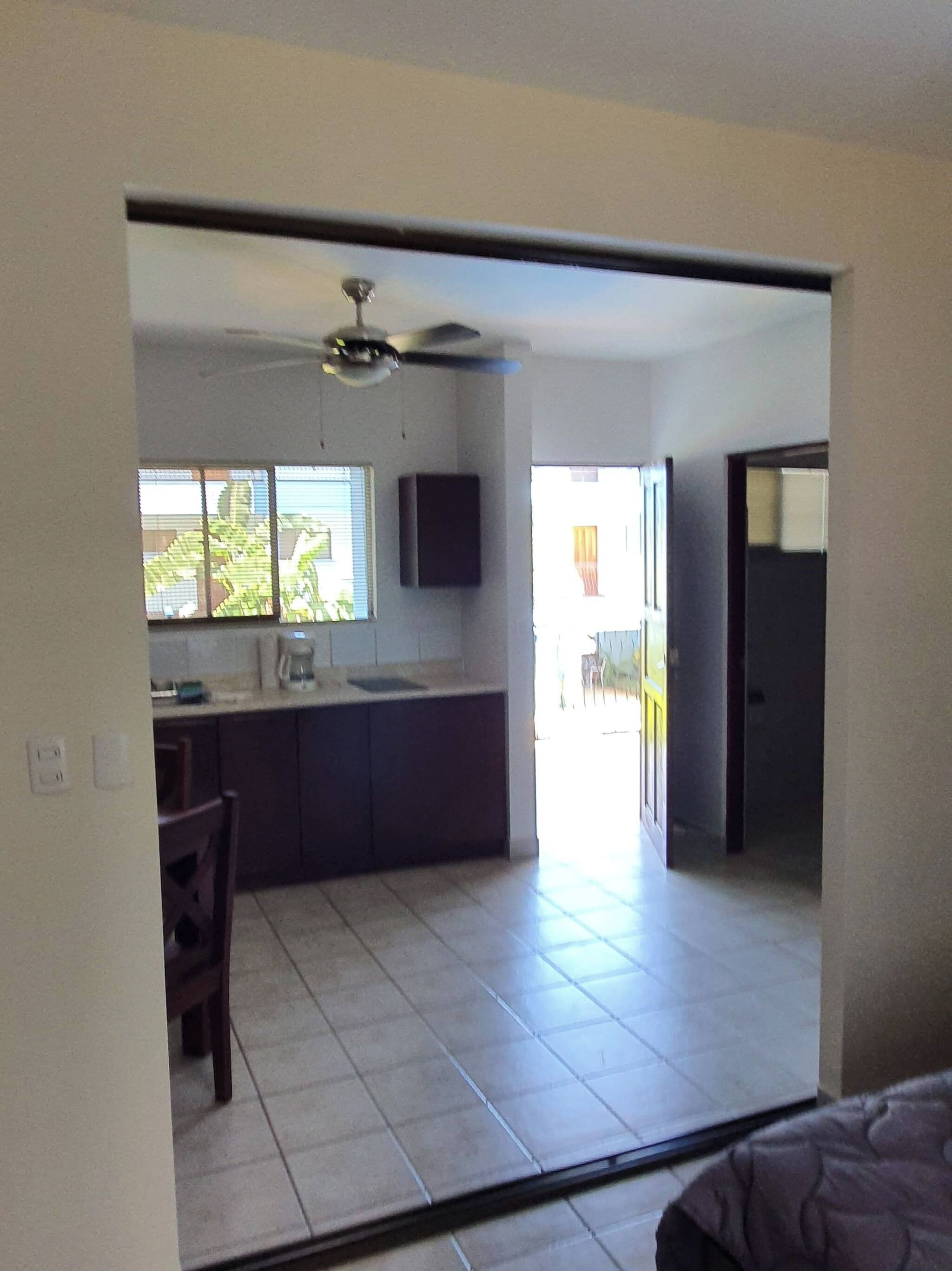 Cozinha com bancada escura, ventilador de teto e janela com persianas.