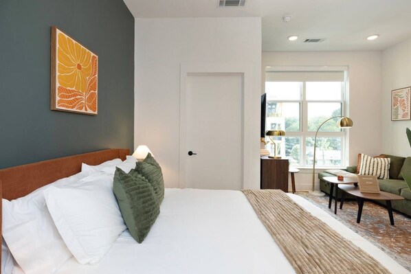 A hotel room with a bed, a desk, a chair, and a window. - NoDa Studio | Free Parking + Gym | Near Uptown (Charlotte)