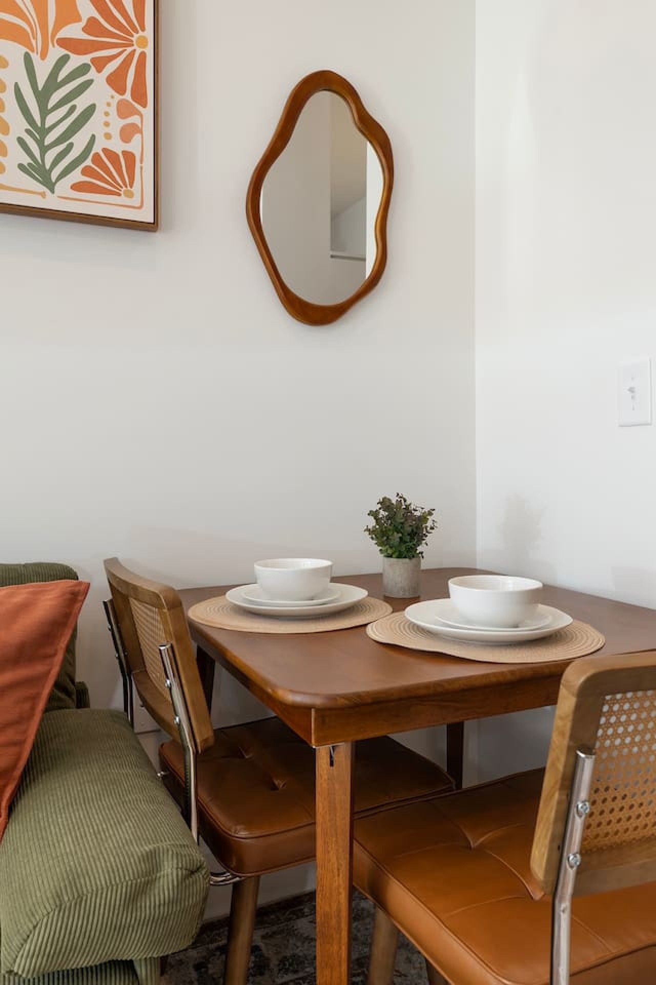 Una mesa de comedor con dos cuencos y platillos blancos, rodeada de sillas de madera con asientos acolchados.