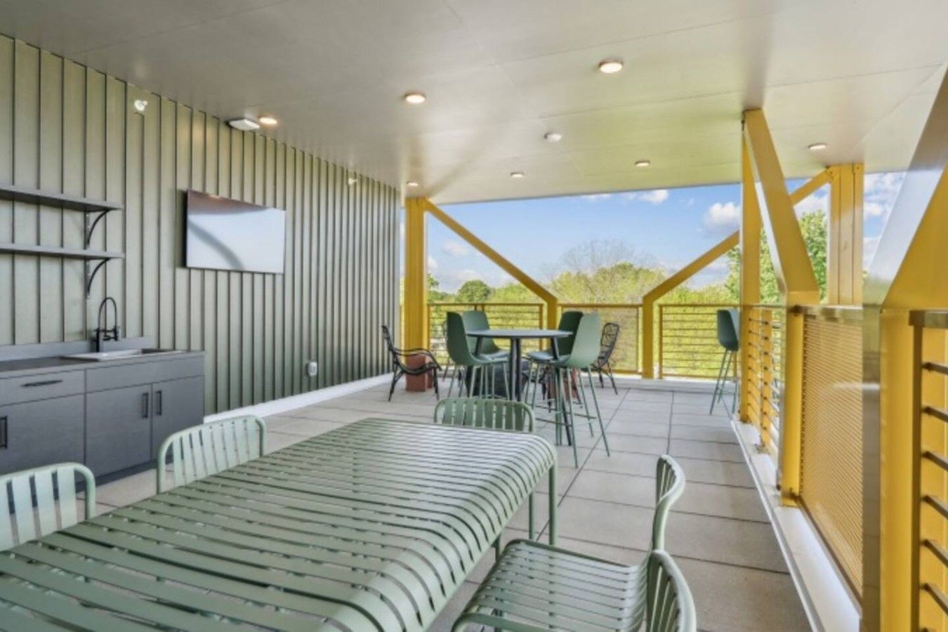 A covered outdoor seating area with a table and chairs, a sofa, and a built-in bench.
