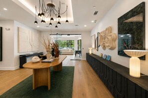 A modern interior with a wooden dining table, black console, and abstract wall art. - NoDa Studio | Free Parking + Gym | Near Uptown (Charlotte)