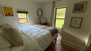 A bedroom with a bed, a chair, a window, and wall decorations.