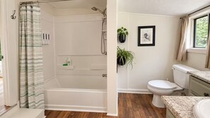 A bathroom with a shower, toilet, sink, and a potted plant.