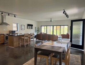 Una cocina moderna con comedor, ventanas amplias y un ventilador de techo.