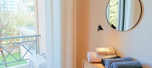 Habitación de hotel con balcón, un espejo, una mesita de noche con toallas y vistas al exterior.