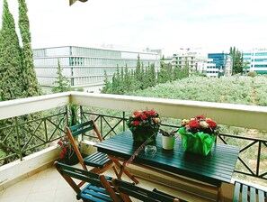 Ein Balkon mit Tisch, Stühlen und Topfpflanzen.