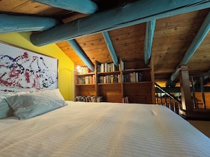 A bedroom with a large bed, a bookshelf, and a painting on the wall. - Comfortable chalet for nature lovers - near Portes du Soleil skiing area (Val-d'Illiez)
