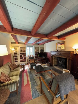 A cozy living room with a fireplace, wooden beams, a sofa, a coffee table, and a bookshelf. - Comfortable chalet for nature lovers - near Portes du Soleil skiing area (Val-d'Illiez)