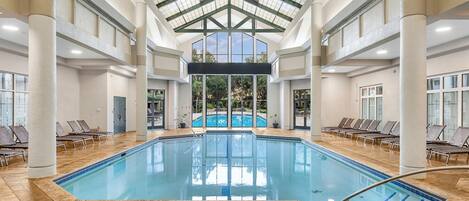 An indoor swimming pool with a high ceiling and large windows.