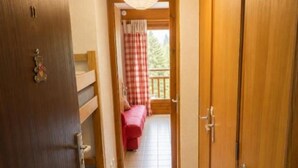 Ein Korridor mit Blick auf einen Balkon, der ein Schachbrettmuster-Vorhang, Holztüren und eine hängende Leuchte zeigt.