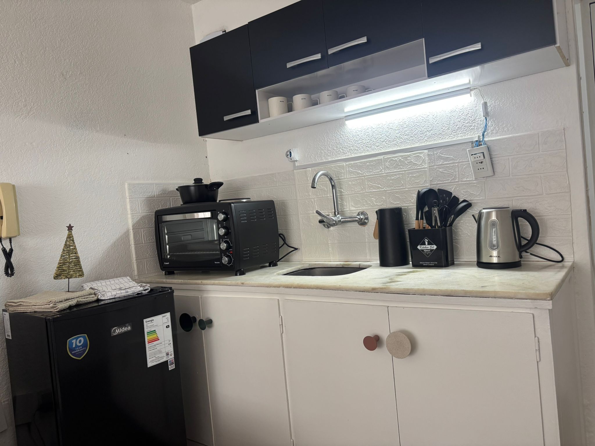 A compact kitchenette with a built-in toaster oven, a sink, and a kettle.