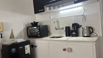 A compact kitchenette with a built-in toaster oven, a sink, and a kettle.