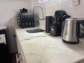 A kitchen with a sink, a toaster, a kettle, and a utensil holder.