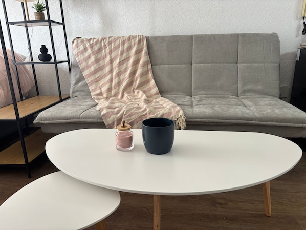 A living room with a grey sofa, a white coffee table, and a small round table.