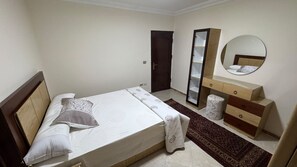 A bedroom with a bed, a dresser, a mirror, and a door. - Hotel apartment view pyramids (Giza Governorate)