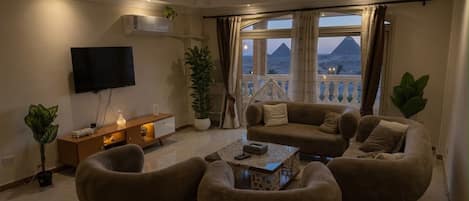A living room with a sofa set, a coffee table, a TV, and a view of a mountain.