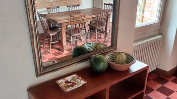 Un comedor con una mesa y sillas de madera, un espejo en la pared y un suelo a cuadros.