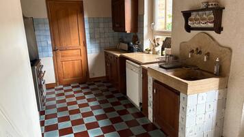 Uma cozinha com piso xadrez, armários de madeira, uma pia e uma janela.
