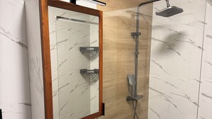 A bathroom with a wooden-framed mirror, a shower with a handheld showerhead, and marble-patterned walls. - Monte Cara (Mindelo)