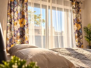 A bedroom with a bed, curtains, and a window.