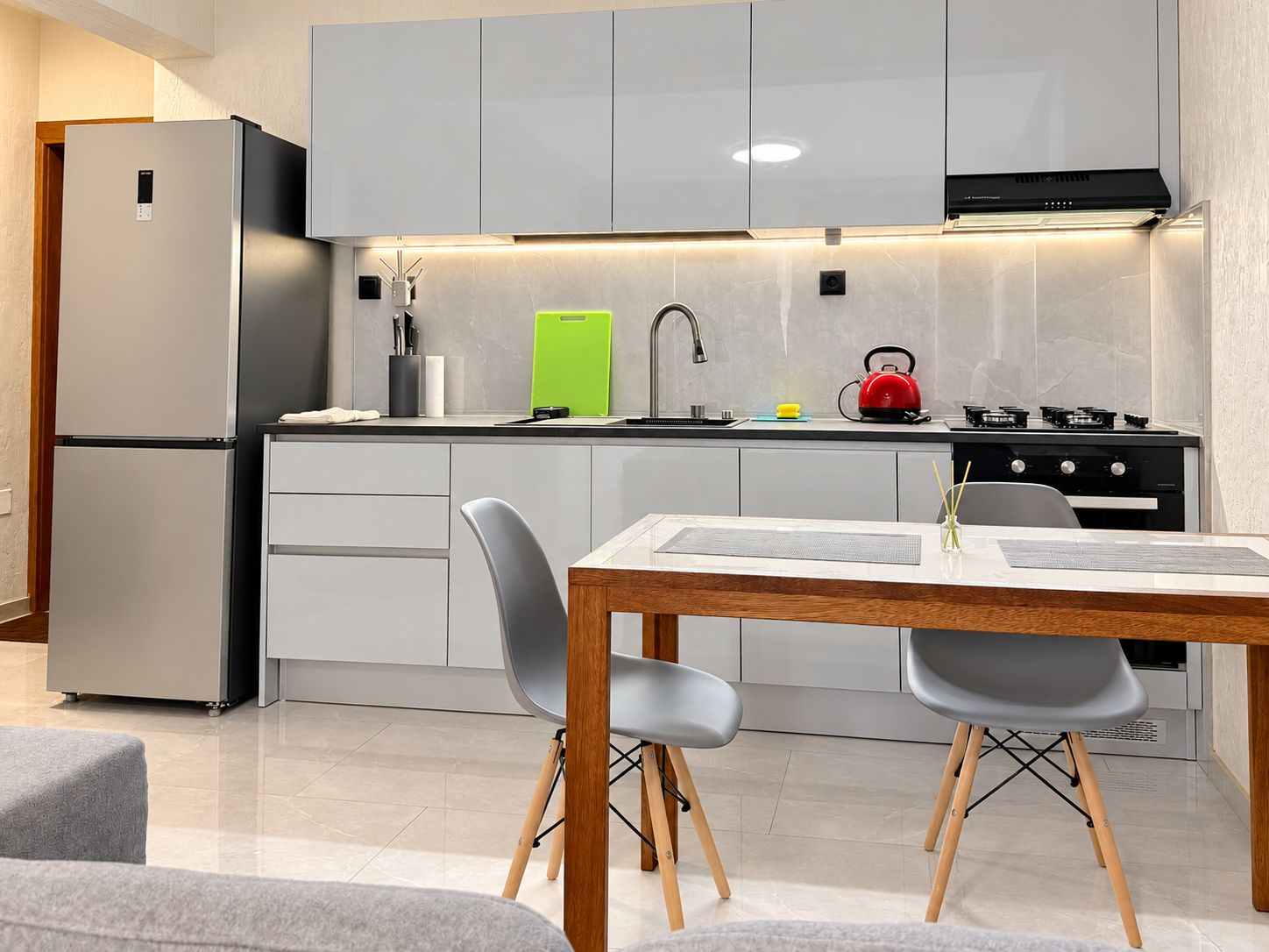 Eine moderne Küche mit Einbaukühlschrank, Herd und Essbereich mit Tisch und Stühlen.