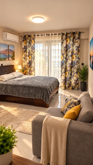 Un dormitorio moderno con una cama, un sofá, una planta en maceta y un cuadro en la pared.