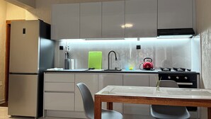 A modern kitchen with a built-in refrigerator, a stove, and a dining area with a table and chairs. - Monte Cara (Mindelo)