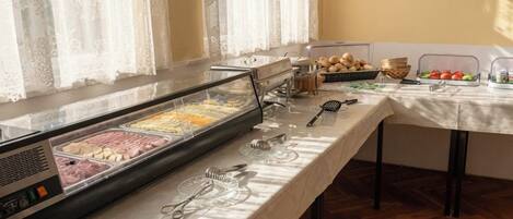 Un buffet proposant une variété de plats, de couverts et une fenêtre ornée de rideaux légers.