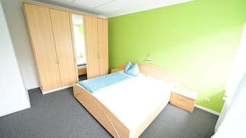 A bedroom with a bed, a wardrobe, a nightstand, and a green wall.