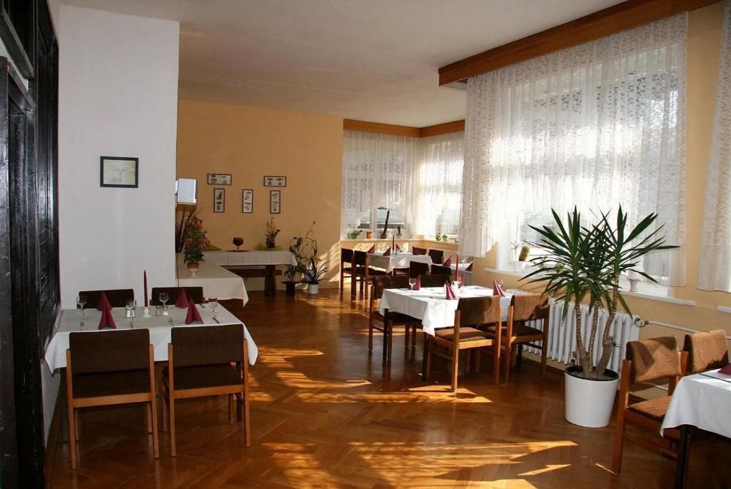 Un comedor con varias mesas y sillas, una planta en maceta y cuadros en las paredes.