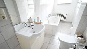 A modern bathroom with a sink, toilet, and bathtub.