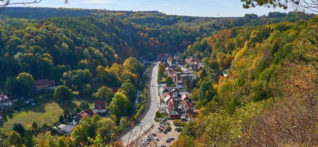 Une ville nichée dans une vallée, traversée par une route, et entourée de forêts denses.