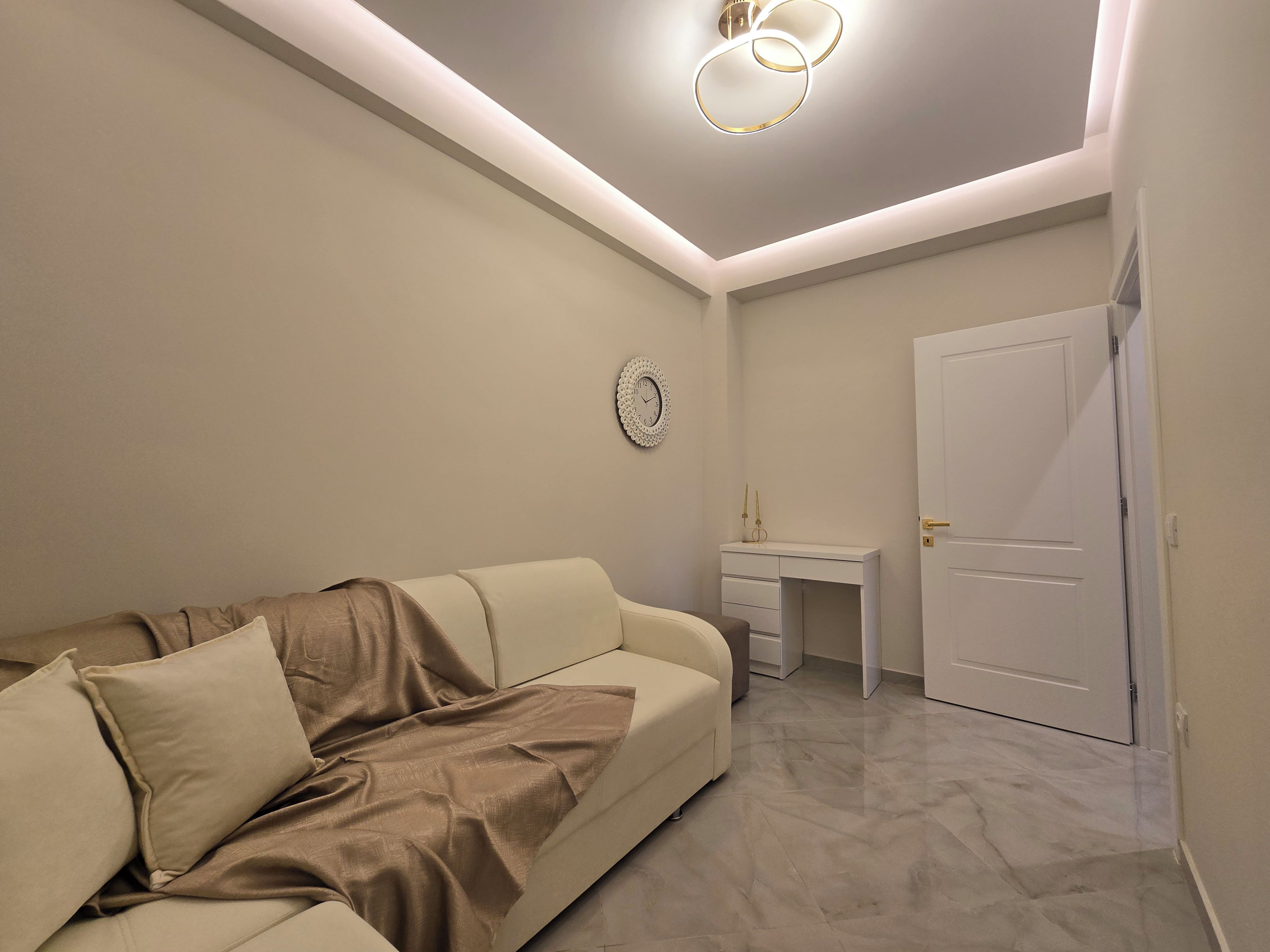 Un dormitorio moderno con un sofá, un escritorio y una puerta.