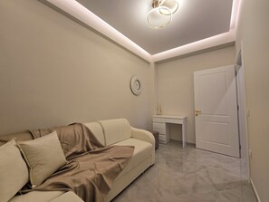 Un dormitori modern amb un sofà, un escriptori i una porta.