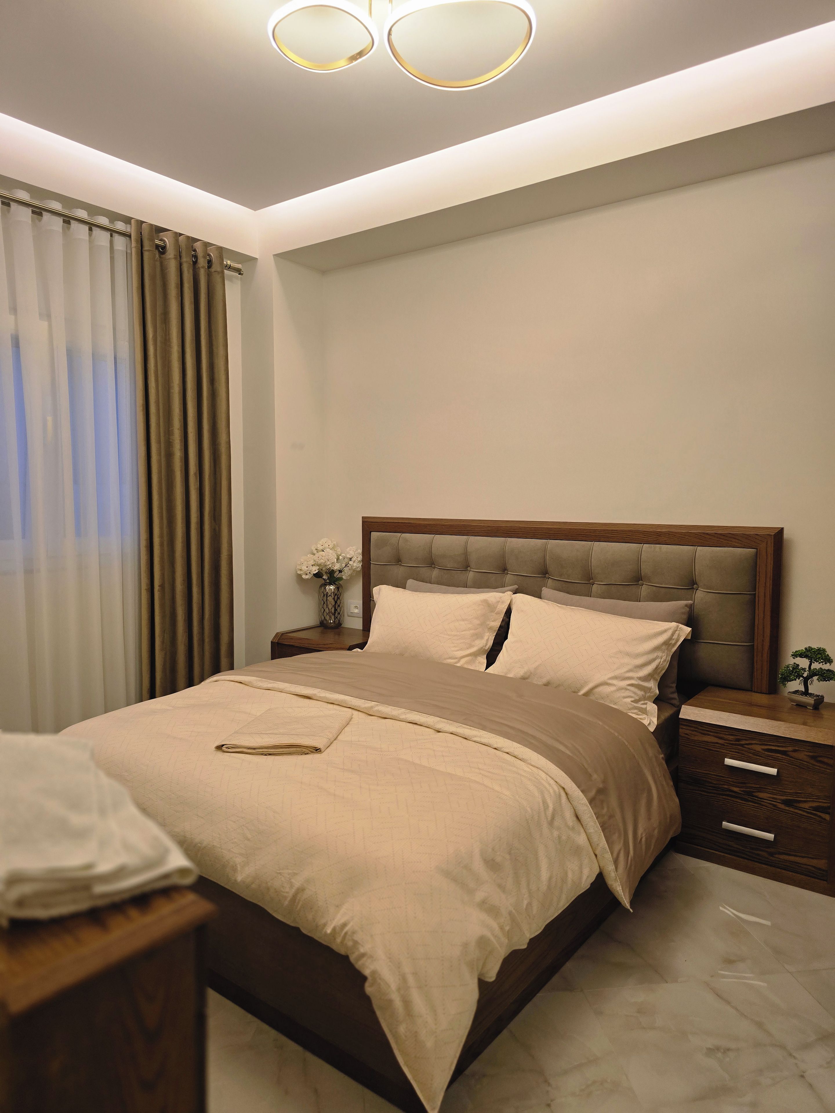 Un dormitorio moderno con una cama grande, mesitas de noche y una lámpara de techo.