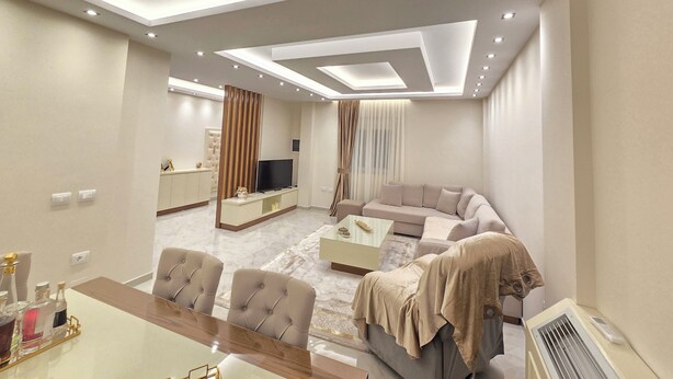 Ein modernes Wohnzimmer mit einer Couch, einem Fernseher und einem Essbereich mit Stühlen und einem Tisch.