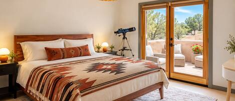 A bedroom with a large bed, a telescope, and a sliding glass door leading to an outdoor patio.