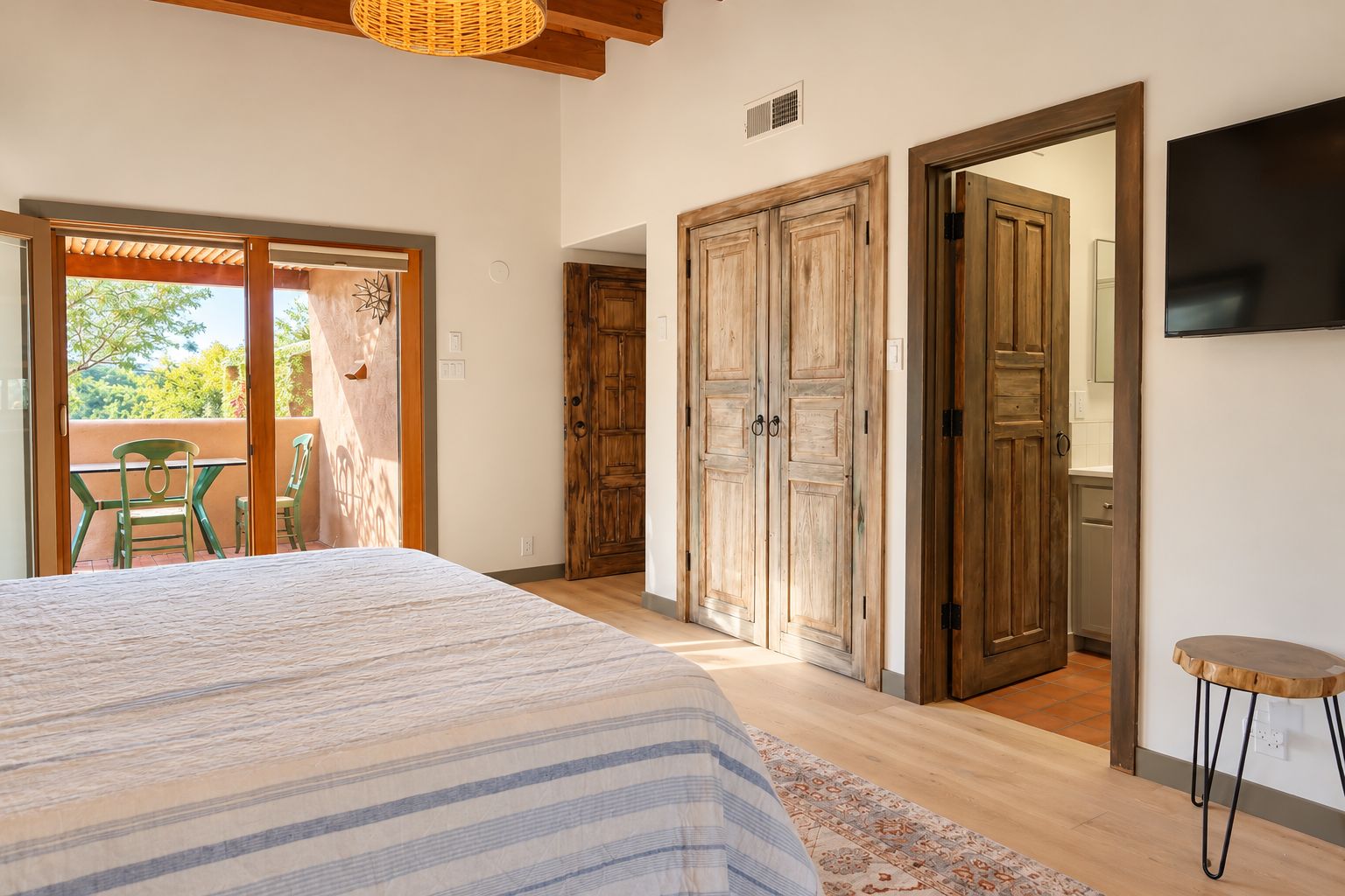 A bedroom with a bed, wooden wardrobe, and a TV.